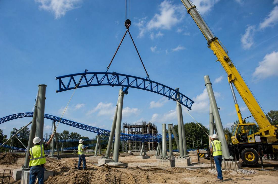 Crane lifting a coaster track section at a park construction site